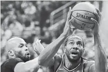  ?? FRANK GUNN THE CANADIAN PRESS ?? Toronto Raptors forward Kawhi Leonard drives to the basket as Minnesota Timberwolv­es forward Taj Gibson defends during first-half action in Toronto on Wednesday. The Raptors won the game 112-105, giving the team five straight wins to start the season.