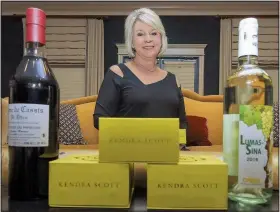  ?? Arkansas Democrat-Gazette/JOHN SYKES JR. ?? Cindy Fields shows off bottles from O’Looney’s Wine &amp; Liquor and jewelry boxes from Kendra Scott, among the auction items at the Vine &amp; Dine benefit for the Wildwood Academy of Music and the Arts on Friday.