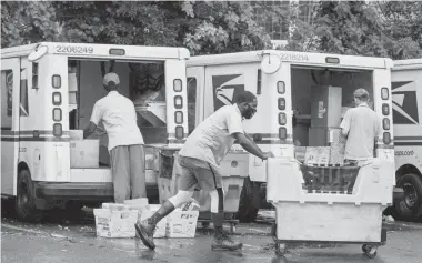  ?? J. SCOTT APPLEWHITE/AP ?? Letter carriers load mail trucks for deliveries at a U.S. Postal Service facility in McLean, Va. The 2020 presidenti­al election could hinge on whether the government agency runs smoothly.