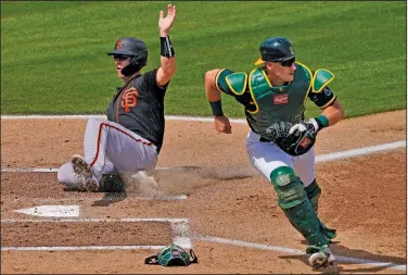  ?? Associated Press ?? Safe: San Francisco Giants' Buster Posey scores on a base hit by Mauricio Dubon as Oakland Athletics catcher Sean Murphy waits for the throw during the first inning of a spring training baseball game Monday in Mesa, Ariz.