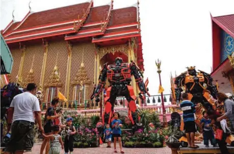  ??  ?? People enjoying giant metal statues inspired by the Transforme­rs franchise, by Ban Hun Lek metalwork, at Wat Tha Kien Buddhist temple in Nonthaburi.