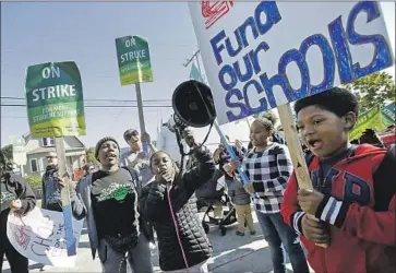  ?? Jeff Chiu Associated Press ?? STUDENT Damyha Gates, 9, speaks through a bullhorn next to her mother, teacher Myeisha Jones, center left, at a rally by teachers, parents and supporters outside Manzanita Community School in Oakland.