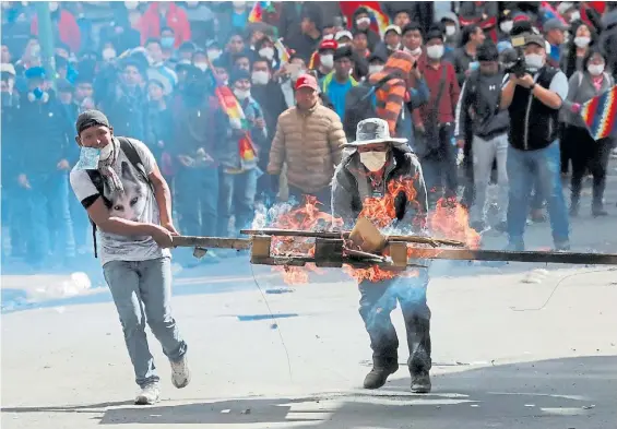  ?? RTR ?? La furia. Los partidario­s de Evo marcharon ayer por el centro de La Paz y provocaron incendios con maderas encendidas. Reclaman su regreso.