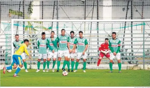  ?? ATLÉTICO SANLUQUEÑO ?? Juanfe se dispone a lanzar un libre directo sobre la portería defendida por Isma Gil ante una poblada barrera.