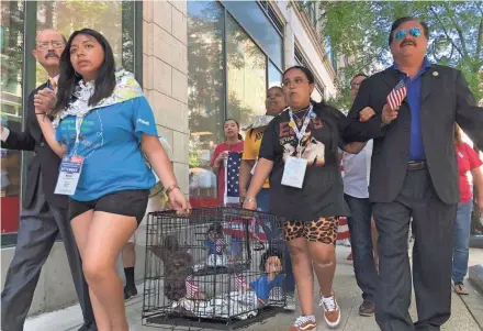  ?? MARISA PERYER / MILWAUKEE JOURNAL SENTINEL ?? Domingo Garcia, right, president of the League of United Latin American Citizens, marches with student activists to the Milwaukee office of U.S. Ron Johnson on Friday. The students carried an animal cage holding a baby doll wrapped in tin foil, mimicking conditions for children reported at the U.S.-Mexico border.