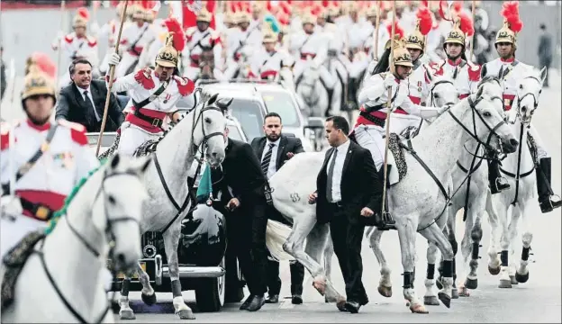  ?? ANTONIO LACERDA / EFE ?? Bolsonaro recorrió la principal avenida de Brasilia en un Rolls-Royce descapotab­le, escoltado por caballos a los que les costó mantener la formación