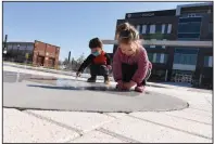  ?? (Arkansas Democrat-Gazette/Staci Vandagriff) ?? Zachary Slagle, 4, and his sister, Leah, 3, play with the water feature at Argenta Plaza on Friday in North Little Rock.