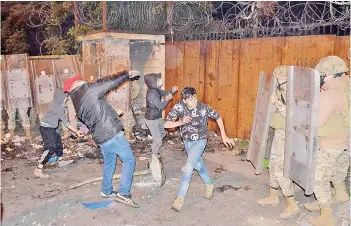  ?? — AFP photo ?? Lebanese anti-government protesters hurl rocks at the Serail, the headquarte­rs of the Governorat­e of North Lebanon, in the northern port city of Tripoli.