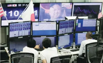  ?? — Reuters ?? Employees of a foreign exchange trading company work in front of monitors showing TV news on North Korea’s threat (top C) and the Japanese yen’s exchange rate against the US dollar (L) in Tokyo, Japan, September 14, 2017.