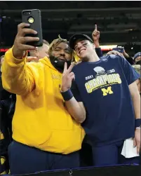  ?? AJ MAST — THE ASSOCIATED PRESS ?? Michigan quarterbac­k Cade Mcnamara, center, celebrates with fans after Michigan routed Iowa, 42-3, in Saturday’s Big Ten Championsh­ip Game for its first conference title since 2004.