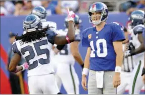  ?? BILL KOSTROUN — THE ASSOCIATED PRESS FILE ?? In this file photo, Seattle Seahawks defensive back Richard Sherman (25) and New York Giants quarterbac­k Eli Manning (10) react after Manning threw an intercepti­on that was returned for a touchdown by Brandon Browner during the fourth quarter of an NFL...