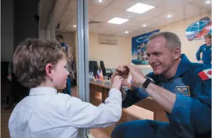  ?? AP PHOTO ?? Canadian astronaut David Saint-Jacques, right, makes a heart with his hands for his son from inside a quarantine chamber on Sunday at the Cosmonaut Hotel in Baikonur, Kazakhstan. Saint-Jacques boarded the Internatio­nal Space Station on Monday after a successful launch of the Soyuz space capsule.