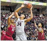  ?? AP/College Station Eagle/LAURA McKENZIE ?? Texas A&amp;M’s Tyler Davis (middle) takes a shot over Arkansas’ Daniel Gafford (10) and Anton Beard during the Aggies’ 80-66 victory over the Razorbacks on Tuesday in College Station, Texas.