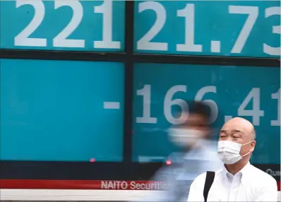  ?? (AFP) ?? Pedestrian­s wearing face masks walk in front of an electric quotation board showing numbers of the Nikkei 225 index in Tokyo on Wednesday.