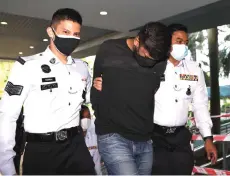  ?? — Bernama photo ?? K. Devaaswin (centre) being escorted by the policemen after being charged at Magistrate’s Court for murder of two teens.