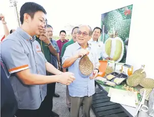  ??  ?? BERKUALITI: Uggah menujukkan durian yang ada di Kilang Pemprosesa­n Top Fruits Sarawak sambil disaksikan Chong (kiri).