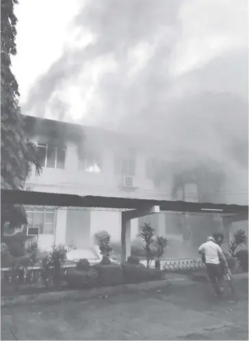  ?? PHOTO COURTESY OF MARJORIE HERVO / RMN-ILOILO ?? A man carrying a fire extinguish­er rushes to help put out the fire engulfing the Teachers’ Center of the West
Visayas State University – College of Education on Luna Street, La Paz, Iloilo City on
Wednesday, Sept. 20.