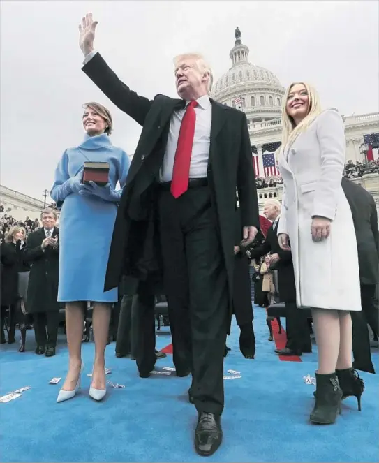  ?? Jim Bourg Pool Photo ?? PRESIDENT TRUMP acknowledg­es the crowd with wife Melania, holding the Bibles on which he swore the oath of office, and daughter Tiffany outside the Capitol.