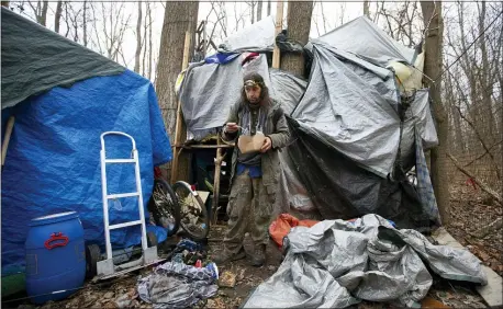  ?? JOHN MUNSON — THE ASSOCIATED PRESS ?? Jose Ortiz eats a boxed meal delivered by volunteers to the residence he built in a homeless encampment Dec. 7 in Ithaca, N.Y. Ortiz tested positive for COVID-19 last month.