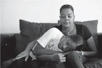  ?? Hyoung Chang, The Denver Post ?? Imani Strong, 10, bottom, and her mother Tristanda Hill, 47, sit in the living room after Imani’s virtual school day. Imani has sickle cell disease.