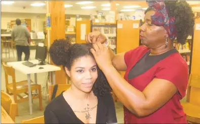  ?? STAFF PHOTOS BY TIFFANY WATSON ?? Waldorf resident Beverly Gunn demonstrat­es how to stretch natural hair for specific hairstyles on Waldorf resident Londen Jordan’s hair during the natural hair public forum at P.D. Brown Memorial Library.