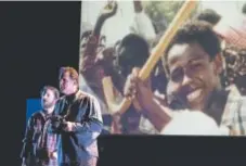  ?? Provided by Curious Theatre ?? Sean Scrutchins, left, and Michael McNeill beneath a projection of Paul Watson’s Pulitzer Prize-winning photograph in “The Body of an American.”