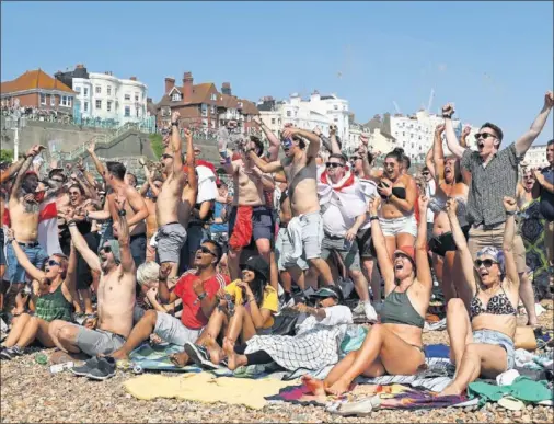  ??  ?? DESDE LA PLAYA. Aficionado­s ingleses en Brighton celebran el pase a semifinale­s de su selección.