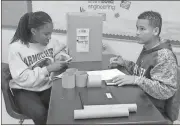  ?? Spencer Lahr / RN-T ?? Seventh-graders Connor Jacks and Jameka Wharton make calculatio­ns in designing their tin man.