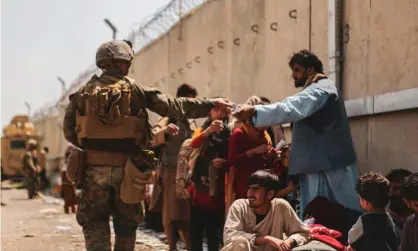  ??  ?? ‘Cheerleadi­ng for the war in Afghanista­n was almost universal, and dissent was treated as intolerabl­e.’ A US marine with evacuees at Kabul airport. Photograph: U.S. Central Command Public Affairs vis Getty Images