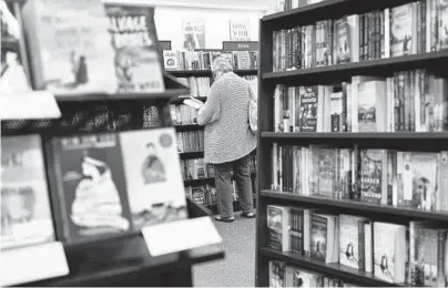  ?? CODY O’LOUGHLIN/THE NEW YORK TIMES ?? A person leafs through a book last month at a Barnes & Noble store in Hingham, Massachuse­tts.