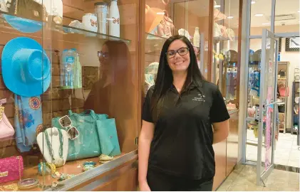  ?? MELINDA MOORE/DAILY SOUTHTOWN ?? Boutique assistant Brittany Ellison stands by display cases with merchandis­e at the Lexus dealership in Orland Park.