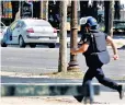  ??  ?? A French policeman runs toward the car seen stationary on the Champs-elysées