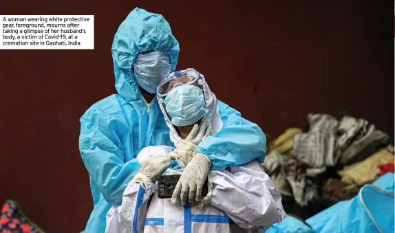  ??  ?? A woman wearing white protective gear, foreground, mourns after taking a glimpse of her husband’s body, a victim of Covid-19, at a cremation site in Gauhati, India