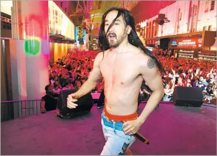  ?? Ethan Miller Getty Images ?? DJ Steve Aoki performs at the Fremont Street Experience in Las Vegas. After running around onstage, he may do push-ups offstage.