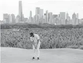  ?? JOHN MINCHILLO/AP ?? John Rahm sinks a putt as the Manhattan skyline looms in the second round of the Northern Trust tournament on Friday in Jersey City, N.J.