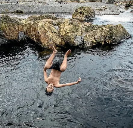  ?? ROBERT KITCHIN/STUFF ?? Angelo Winter-Robati, 14, from Upper Hutt has fun swimming and diving off rocks with his friends in a popular Upper Hutt swimming hole. The temperatur­e reached the high 20s yesterday.