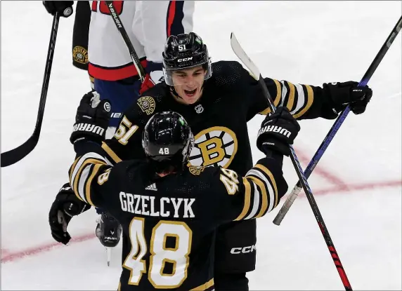  ?? (STAFF PHOTO — STUART CAHILL/BOSTON HERALD ?? Boston Bruins center Matthew Poitras (51) celebrates his goal with defenseman Matt Grzelcyk during an Oct. 3 preseason game against the Capitals at the TD Garden.