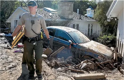  ?? PHOTO: WASHINGTON POST ?? Santa Barbara County police officer Dennis Thomas leads Dina Landi through the home where she was staying when a mudslide struck.