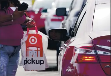  ?? ROGELIO V. SOLIS — THE ASSOCIATED PRESS ?? A Target employee prepares to hand a customer a curbside pickup purchase. Target has doubled the number of parking spaces for its drive up services, to 8,000. Walmart says it will create “pop-up” hubs to meet demand for online orders.