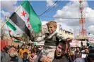  ?? Omar Haj Kadour/AFP/Getty Images ?? A Syrian boy with his face painted in the colours of the Ukranian flag, attends a rally marking 11 years since an anti-regime uprising in Syria’s rebel enclave of Idlib Photograph: