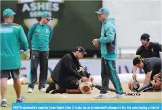  ??  ?? PERTH: Australia’s captain Steve Smith (2nd L) looks on as groundstaf­f attempt to dry the wet playing pitch prior to a start on day five of the third Ashes cricket Test match between England and Australia in Perth.—AFP