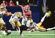  ?? John Bazemore / Associated Press ?? Georgia running back Kenny McIntosh (6) tries to escape from LSU safety Major Burns (28) and defensive tackle Jaquelin Roy (99) in the second half of the Southeaste­rn Conference Championsh­ip game Saturday in Atlanta.