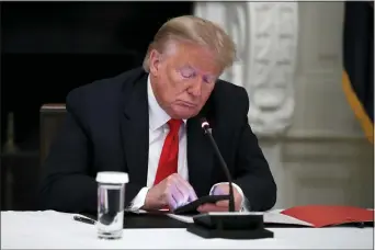  ?? ALEX BRANDON — THE ASSOCIATED PRESS FILE ?? In this Thursday, June 18, 2020 file photo, President Donald Trump looks at his phone during a roundtable with governors on the reopening of America’s small businesses, in the State Dining Room of the White House in Washington.