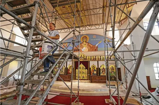  ?? Melissa Phillip photos / Houston Chronicle ?? Houston artist Nick Papas assists in the installati­on of the icons on the dome of St. Anthony the Great Orthodox Christian Church.