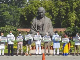  ?? — PTI ?? YSR Congress Party MPs display placards during a protest demanding a CBI probe into the Amravati land scam case in front of Mahatma Gandhi’s statue in the Parliament House complex in New Delhi on Sunday.