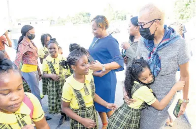  ?? IAN ALLEN/PHOTOGRAPH­ER ?? Fayval Williams, the minister of education and youth, is hugged by a student of Homestead Primary and Infant School in Spanish Town during devotion Tuesday. Williams met with teachers and administra­tors to discuss the triggers of a two-day staff protest last November.