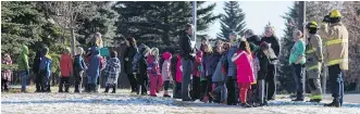  ?? CRYSTAL SCHICK/ CALGARY HERALD ?? Firefighte­rs help guide schoolchil­dren to city buses after emergency crews were called in Wednesday for a suspected carbon monoxide leak at Woodlands Elementary School.