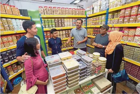  ??  ?? MOHD Naharudin (tiga dari kanan) melayan pelanggan yang datang membeli pelbagai jenis biskut raya di premisnya di Angsana Mall, Johor Bahru.