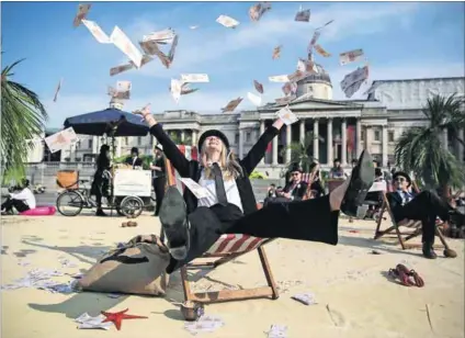  ?? Photo: Neil Hall/Anadolu Agency ?? Wasted: A woman throws fake money in the air at a protest against the unfair debt burden on developing countries during the Global Anti-corruption Summit in London in May.
