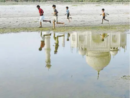  ?? Rajesh Kumar Singh, Associated Press file ?? The iconic Taj Mahal is reflected in the dying Yamuna River, alongside which children play.